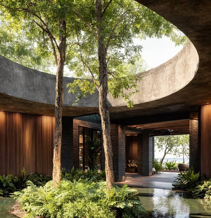 Circular courtyard open to the sky, with trees rising through it and timber-lined rooms around the edge